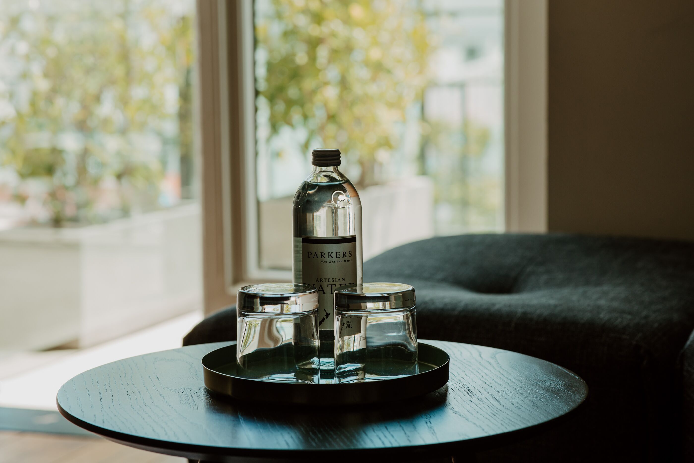 A round table with a bottle and two salt shakers on a tray.