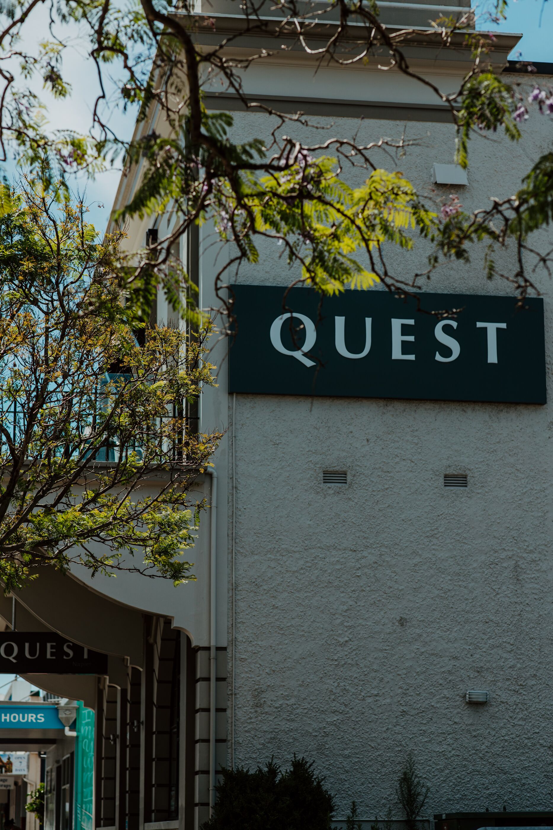 A building with a sign that reads "QUEST" on a textured wall.