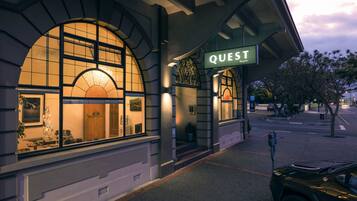 A hotel entrance with a large arched window, a sign reading "QUEST Napier," and a parking meter on the sidewalk.