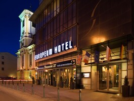 El exterior del Hotel Europa, con un letrero llamativo, una torre de reloj y banderas.
