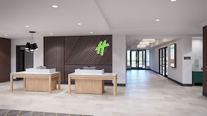 A modern lobby with two reception desks, a patterned wall, and a geometric wall design.