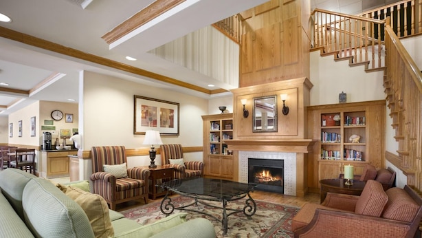 A spacious living room with a fireplace, a staircase, and a dining area in the background.