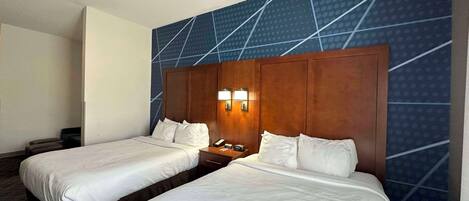 Una habitación de hotel con dos camas individuales, un cabecero de madera y una pared con un diseño geométrico.