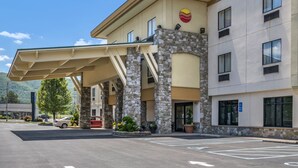 A hotel with a covered entrance, stone pillars, and a parking lot.