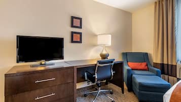 Una habitación de hotel con escritorio, televisión, silla y lámpara.