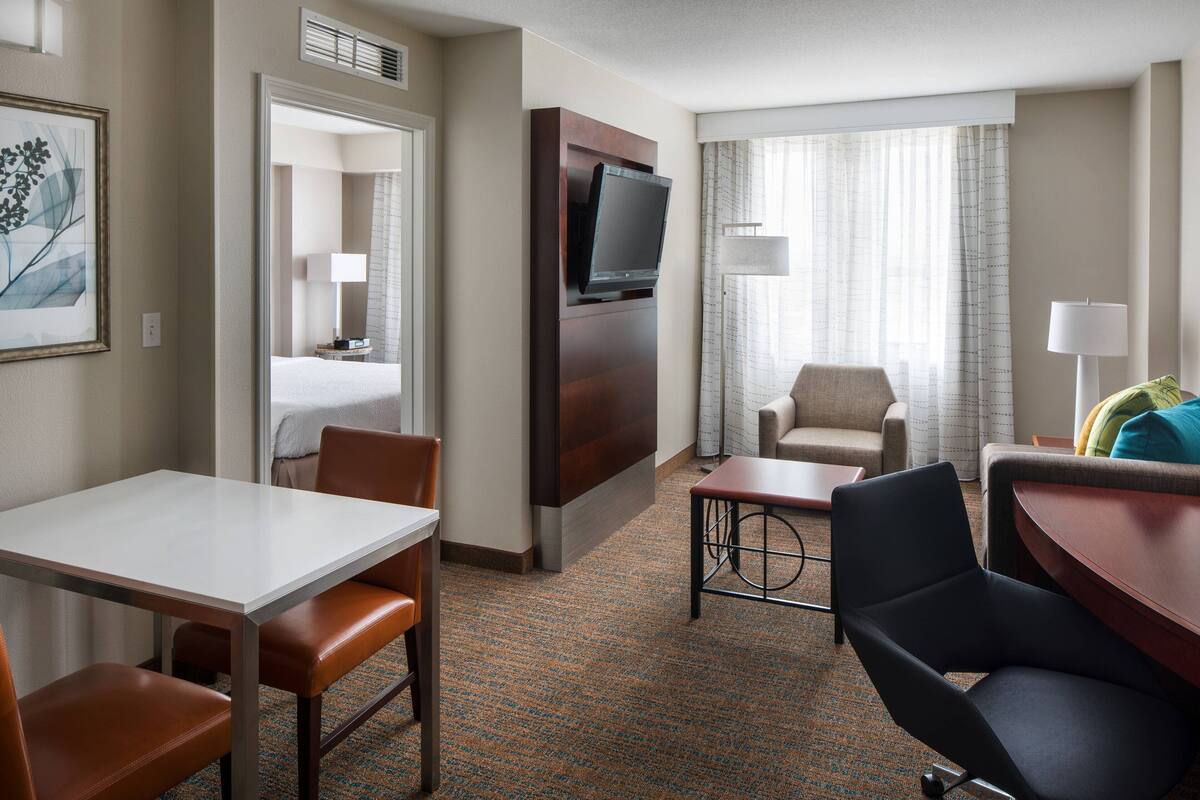 A hotel room with a bed, a TV, a desk, and two chairs.