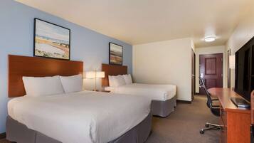 A hotel room with two beds, a desk, and a TV.
