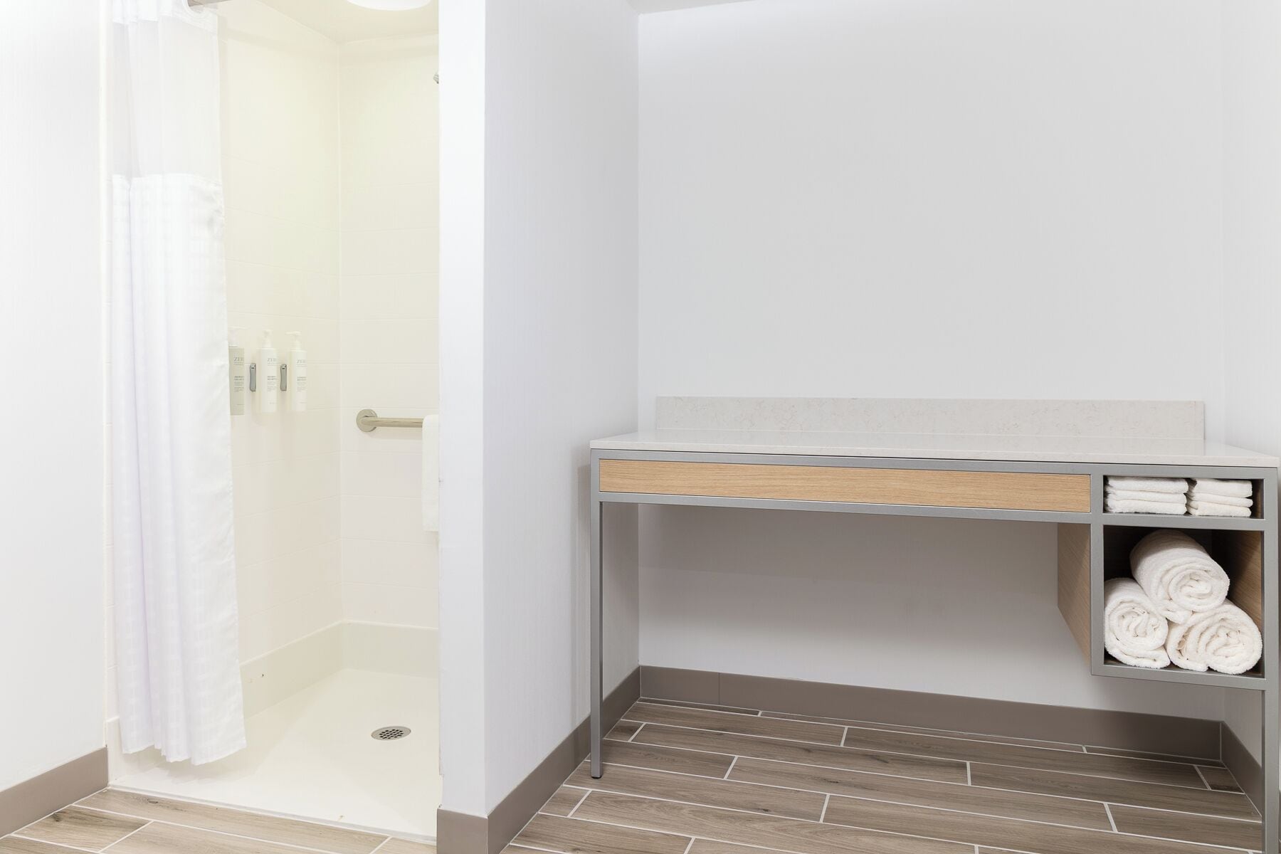 A bathroom with a shower, a towel rack, and a shelf with towels.
