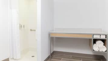 A bathroom with a shower, a towel rack, and a shelf with towels.