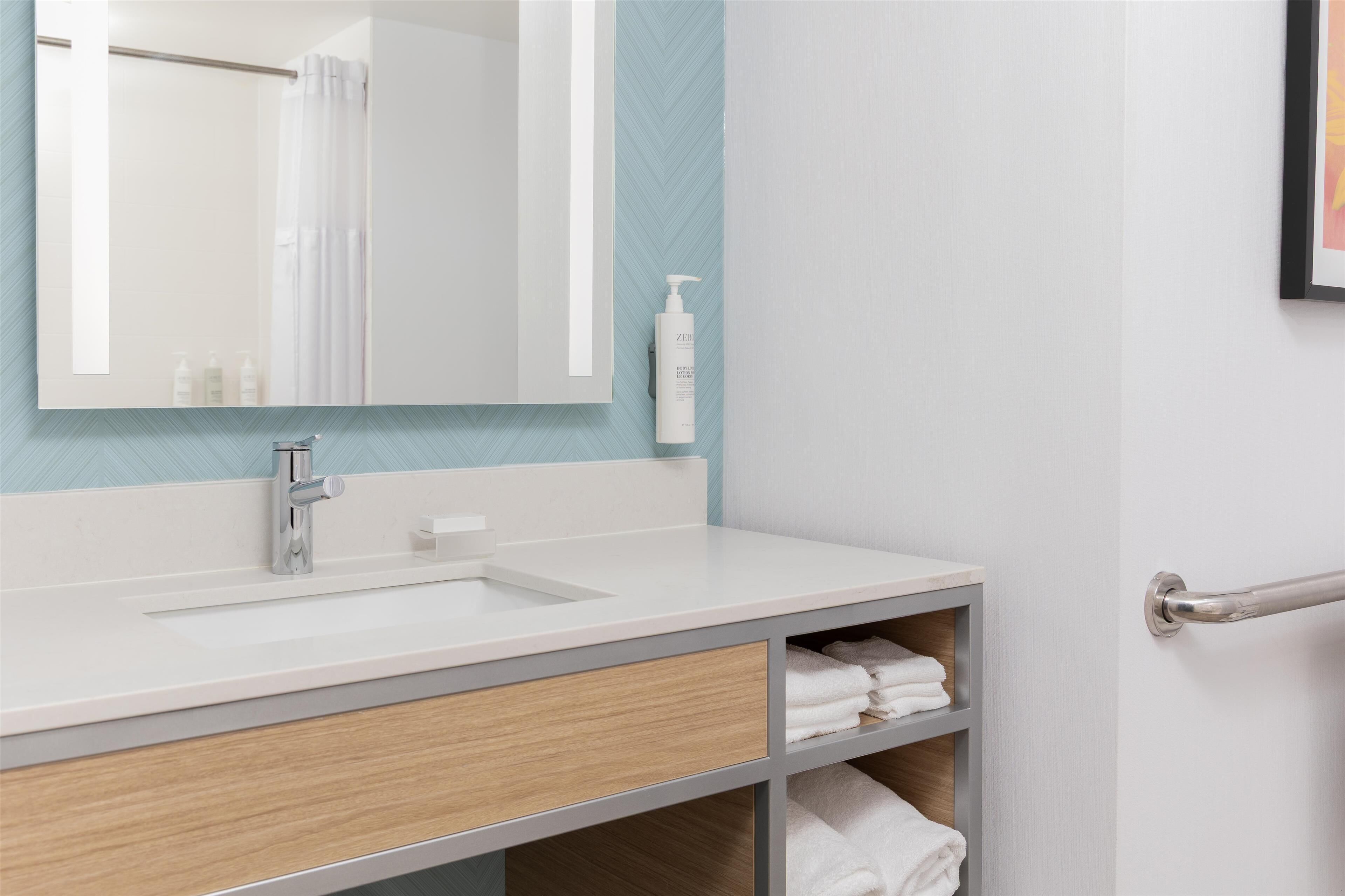A bathroom with a white sink, a mirror, a towel rack, and a shower curtain.