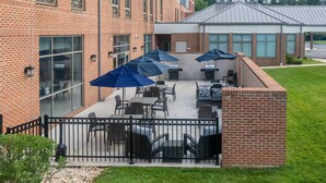 An outdoor patio with brick walls, tables, chairs, and umbrellas. - Hilton Garden Inn Hanover Arundel Mills,  MD (Hanover)