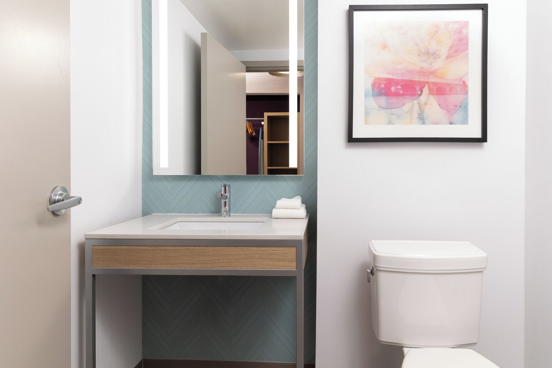 A modern bathroom with a sink, mirror, and toilet.