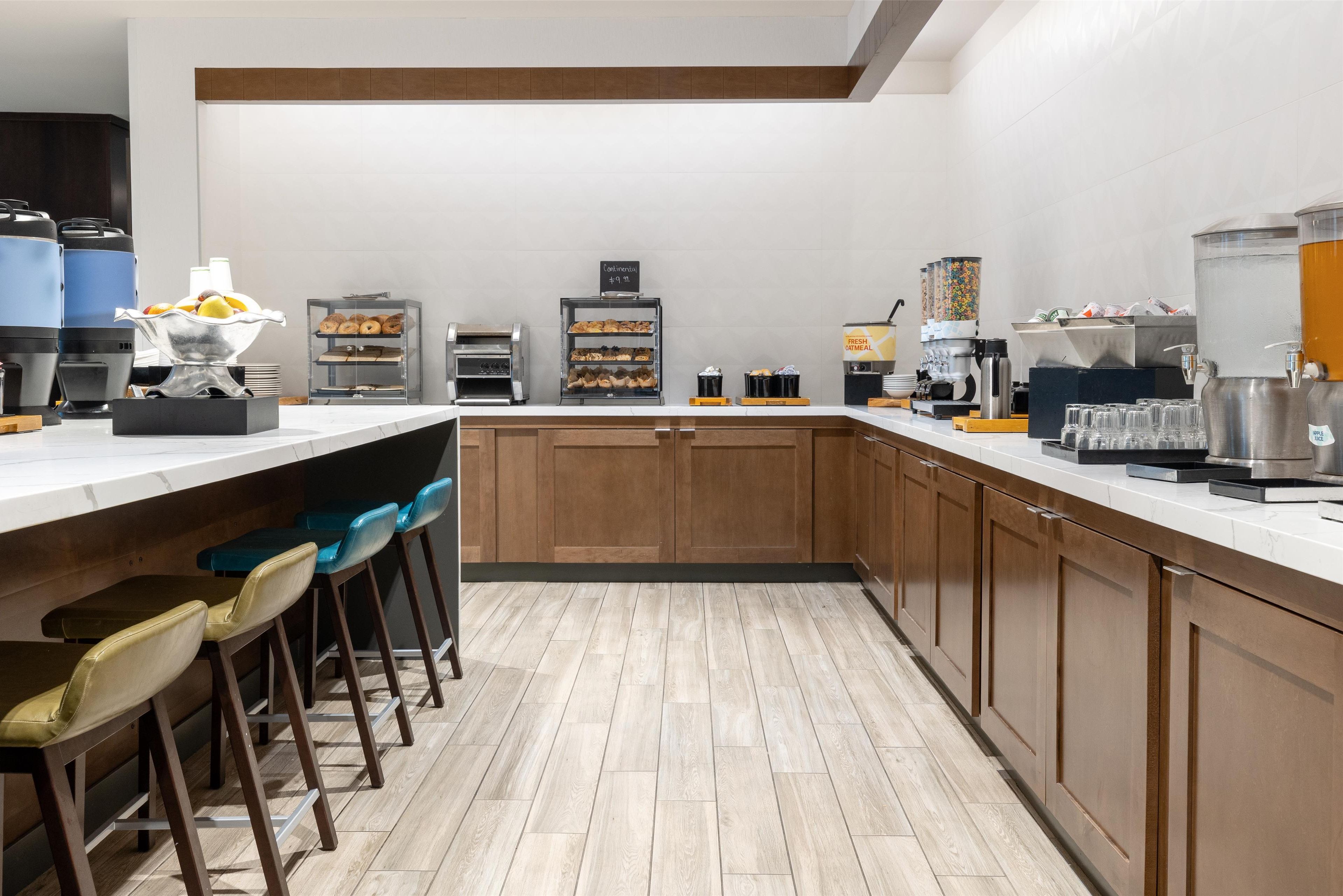 Une cuisine moderne dotée d’un coin bar, équipée de machines à café, d’un distributeur d’eau et d’un panier à fruits.