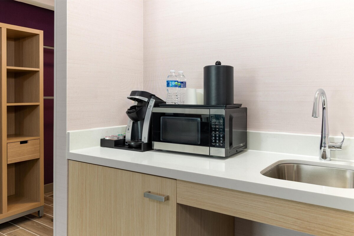 A kitchenette with a microwave, coffee maker, and water bottles.