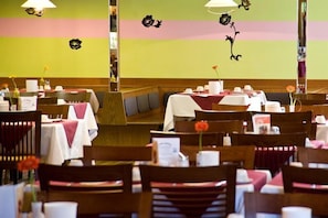 En restaurang med flera bord och stolar, vissa med rosa dukar.