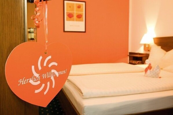 A hotel room with a bed, a nightstand, a lamp, and a framed picture on the wall.