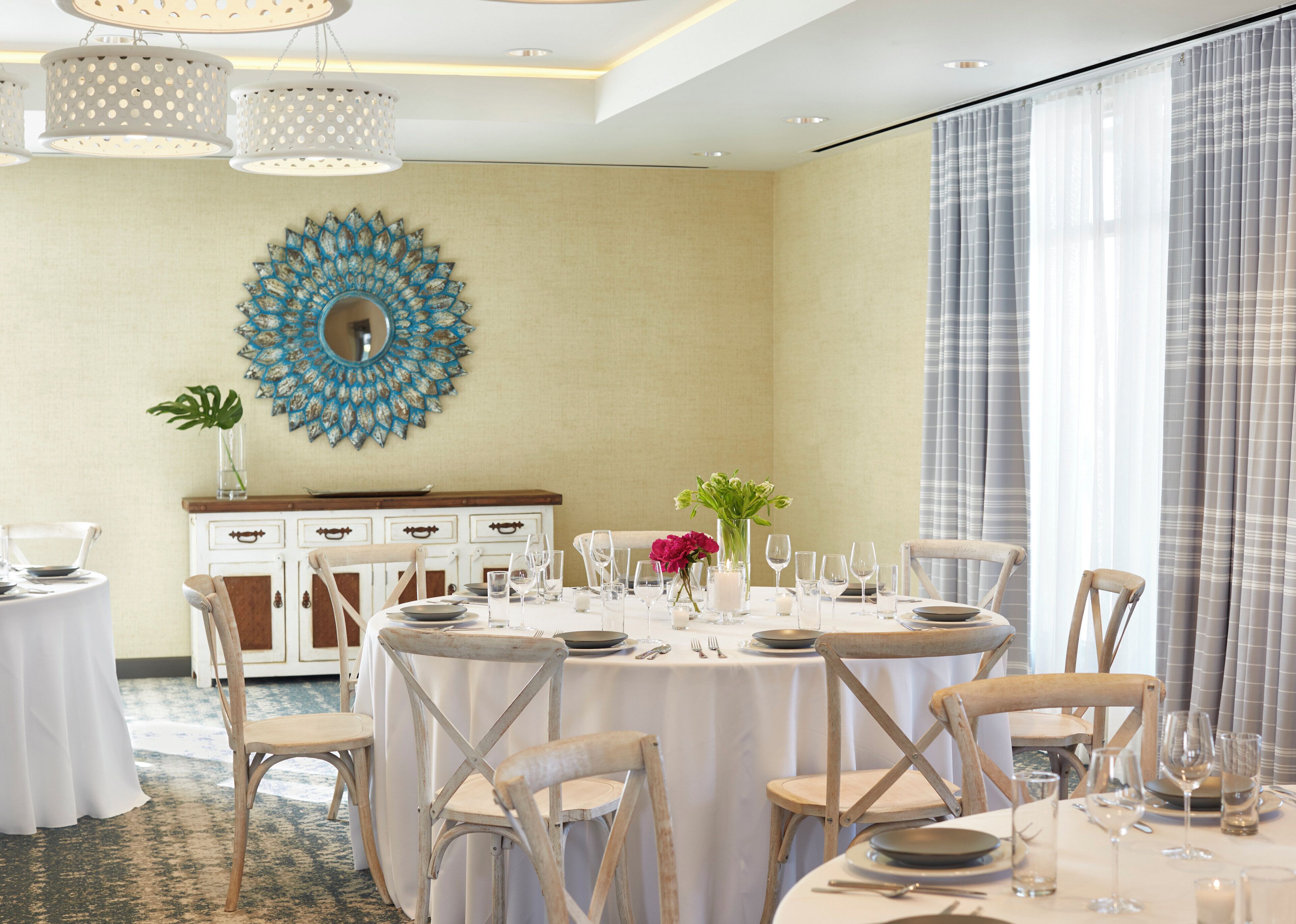 A dining area with round tables, chairs, and a decorative wall piece.