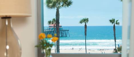 A view of a beach with palm trees, a pier, and the ocean.