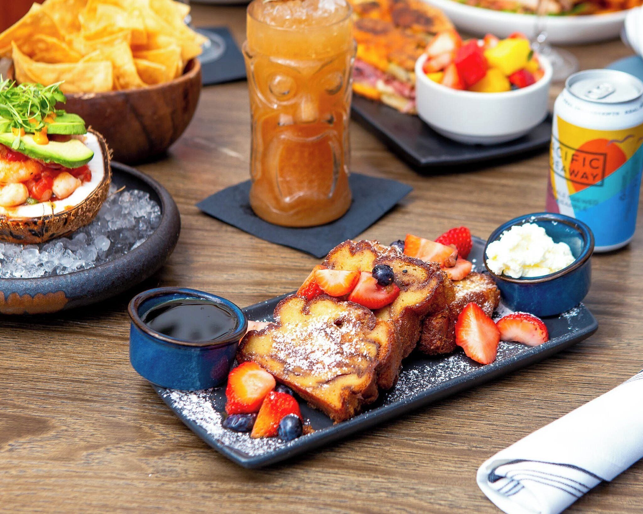 Een ontbijttafel met French toast, aardbeien, bosbessen en een drankje.