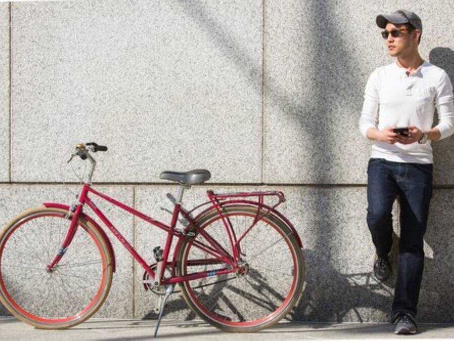Ein rotes Fahrrad, an eine strukturierte Wand gelehnt.