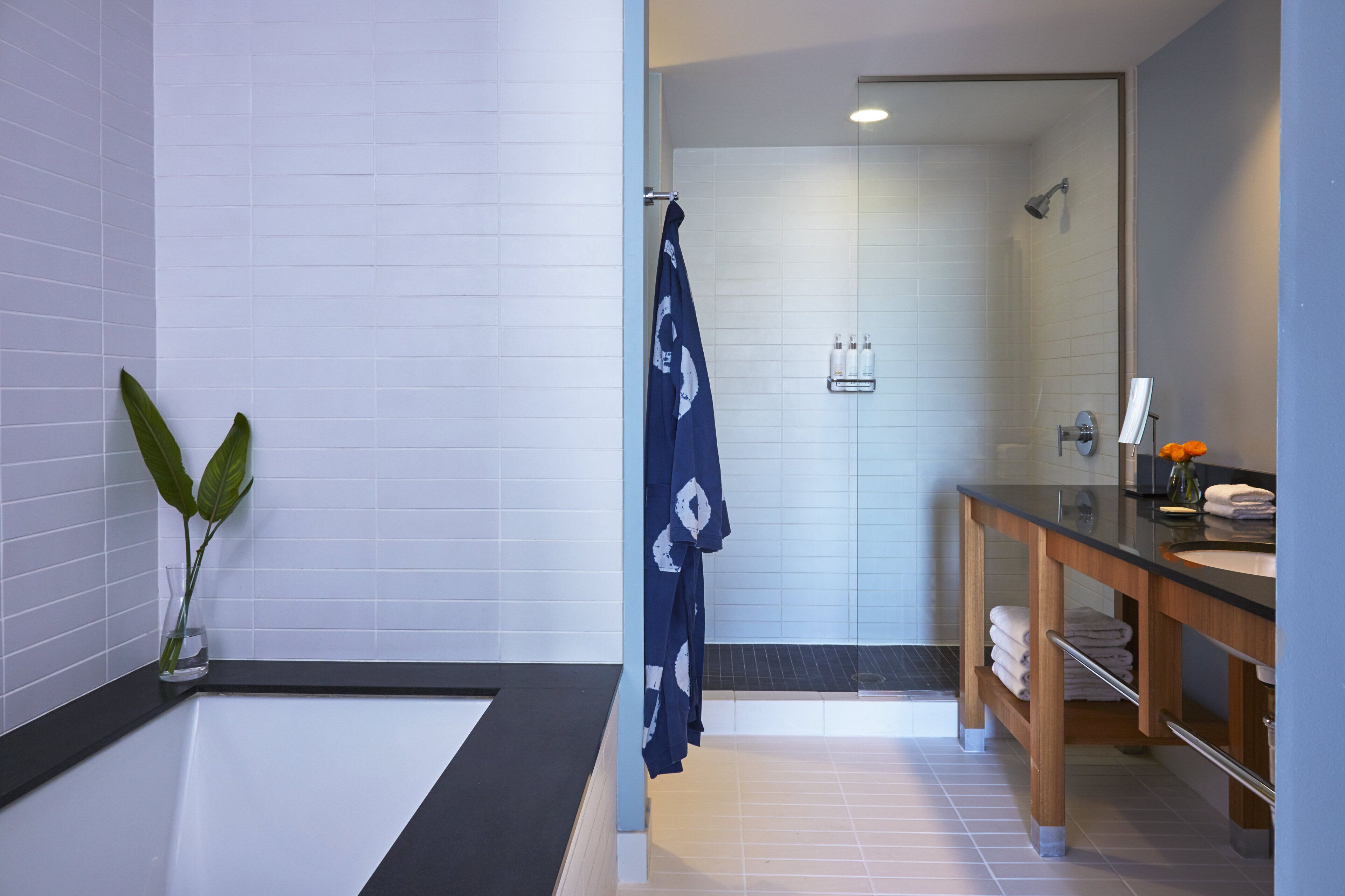 Un baño moderno con una bañera, ducha, tocador con espejo y una planta en maceta.