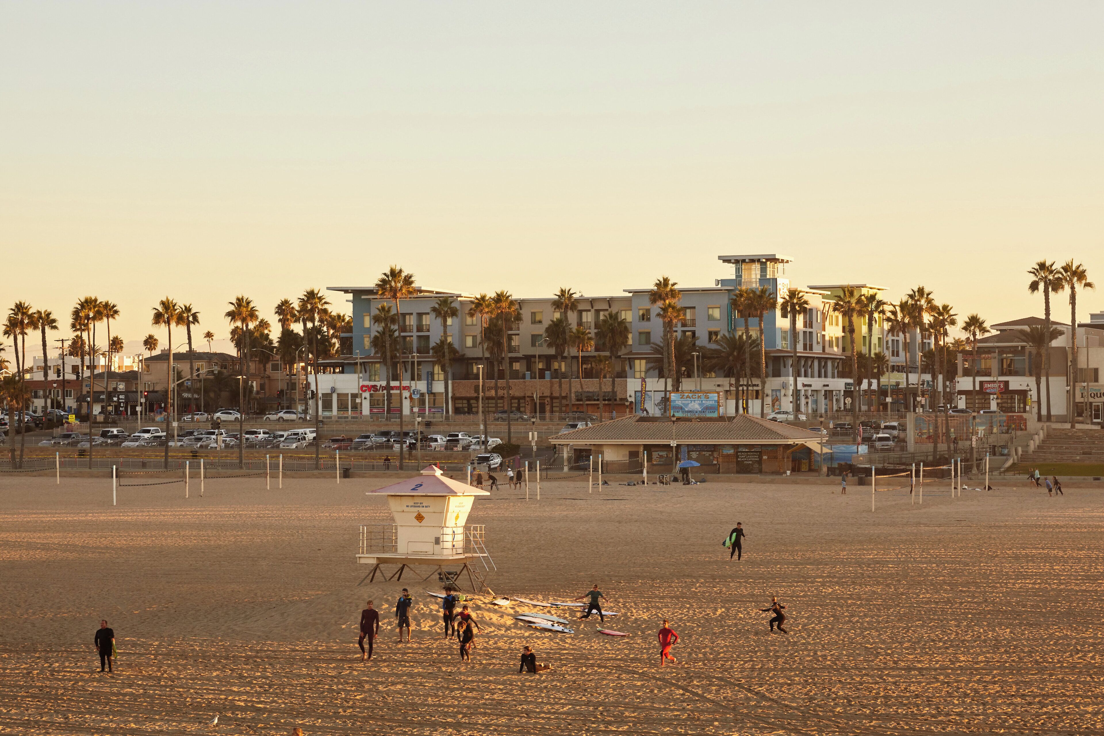Una playa con una torre de salvavidas, palmeras y edificios al fondo.