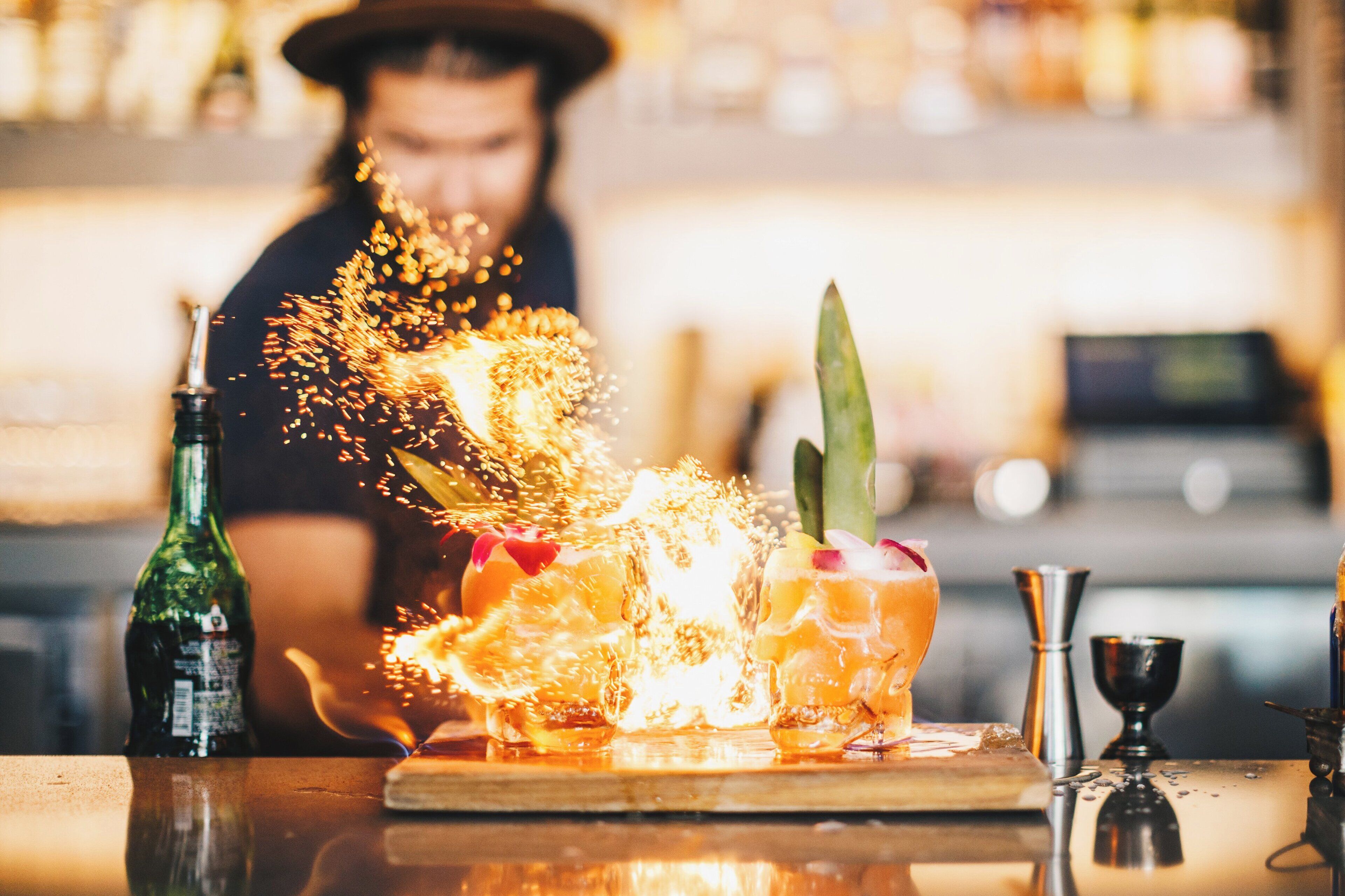 Ein Barkeeper bereitet einen Drink mit einer Flasche Alkohol und einem Glas auf einer Bar vor.