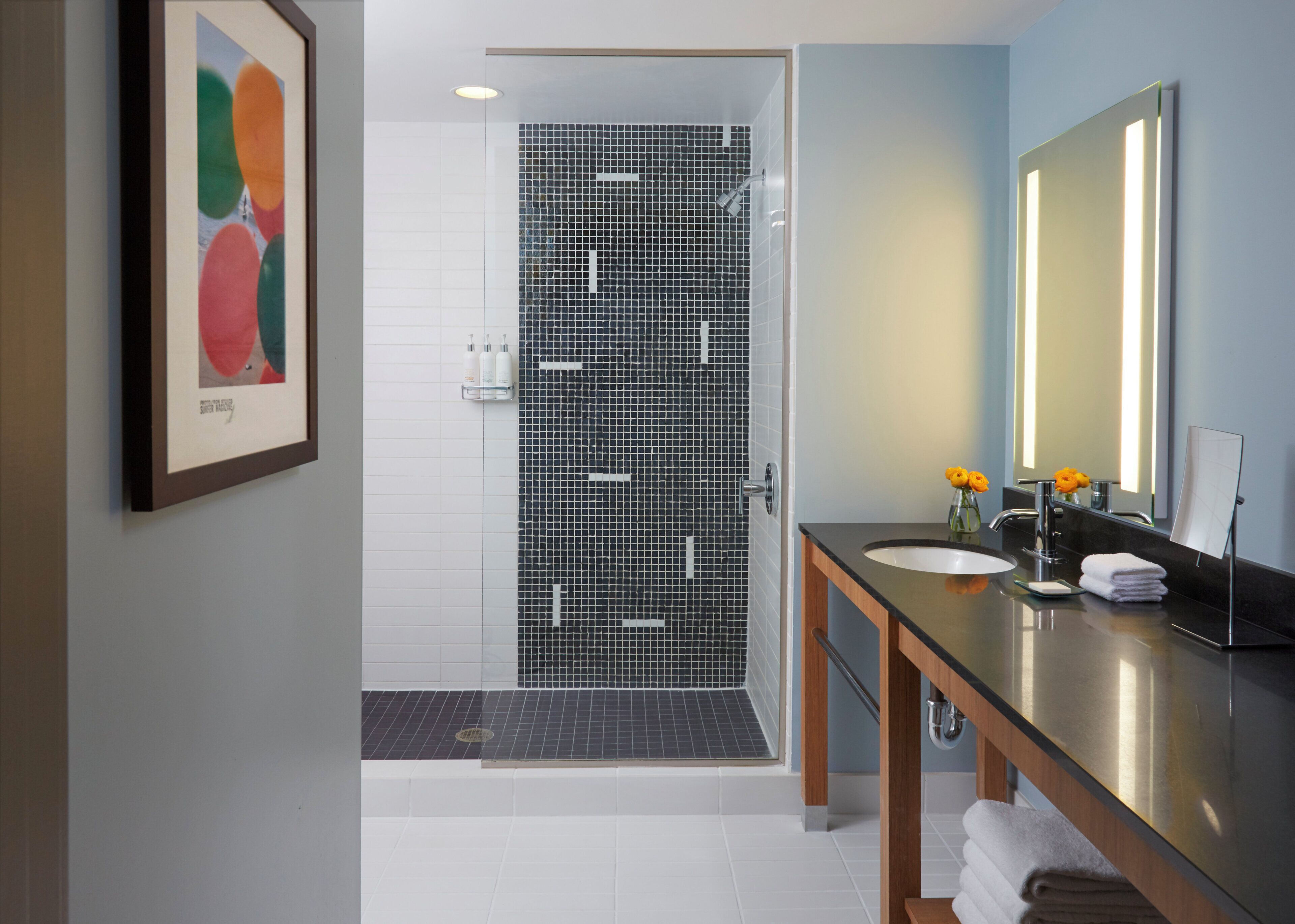 Un baño moderno con ducha, lavabo y espejo.