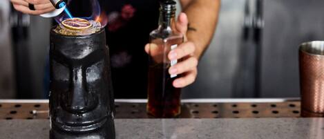 Una persona usando un soplete de butano para encender una vela dentro de una botella negra.
