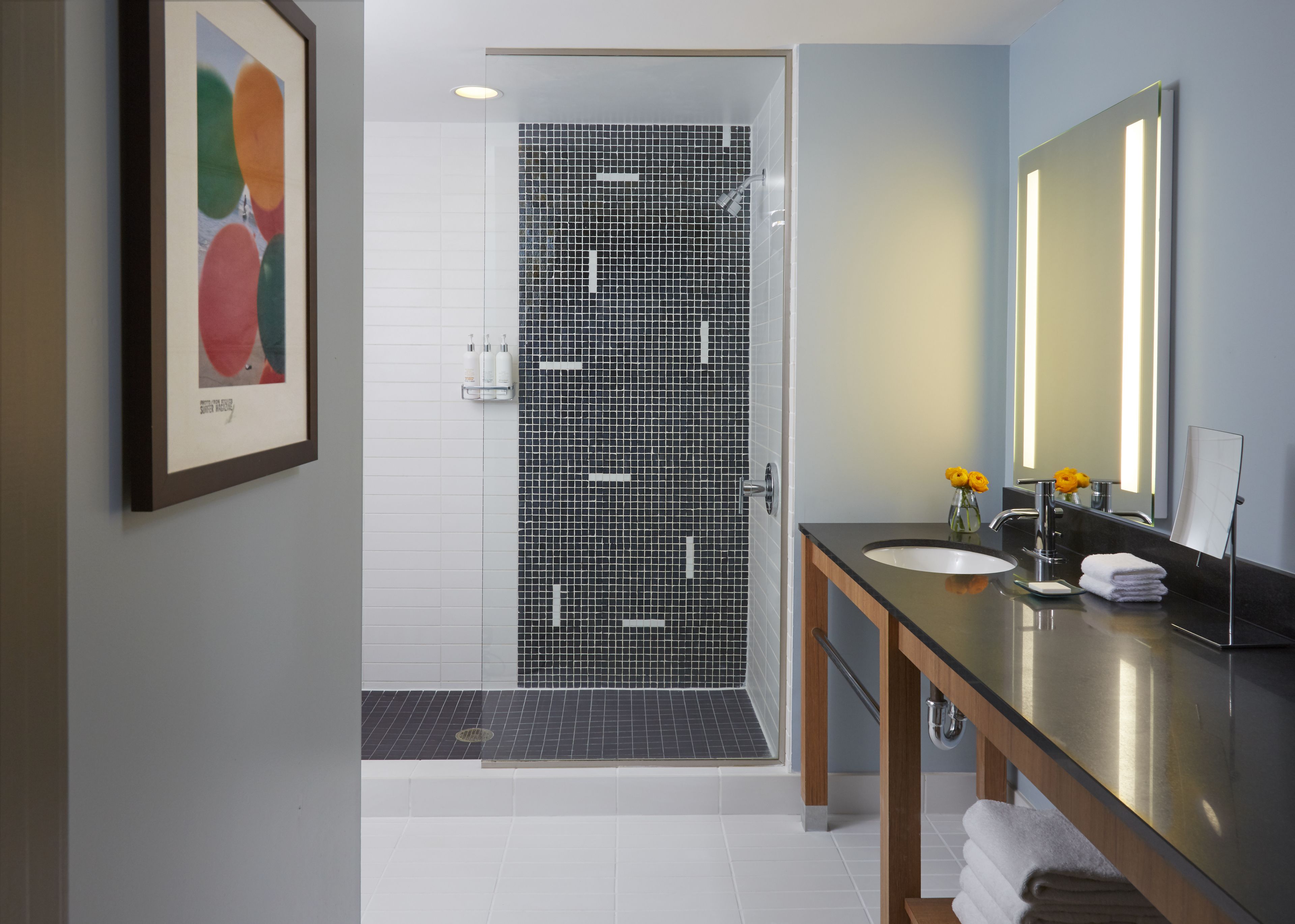 Een moderne badkamer met douche, wastafel en spiegel.