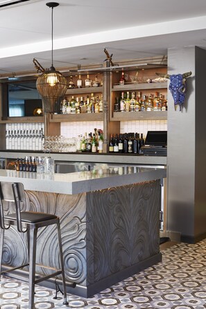 A bar area with a marble countertop, bar stools, a wine rack, and a decorative skull on the wall. - Kimpton Shorebreak Huntington Beach Resort by IHG (Huntington Beach)
