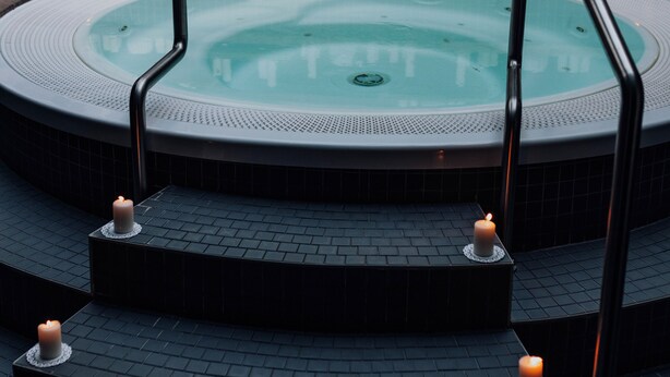 Un área de spa con un jacuzzi circular, escalones que lo conducen y velas colocadas en los escalones.