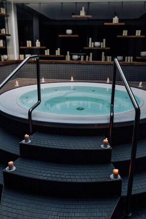 Un área de spa con un jacuzzi circular, escalones que lo conducen y velas colocadas en los escalones.