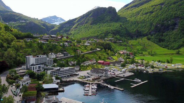 A lakeside hotel with a dock, surrounded by lush greenery and mountains. - Havila Hotel Geiranger (Stranda)