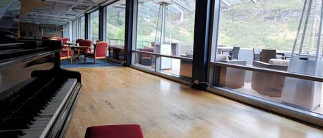 A spacious room with a piano, large windows, and a view of the outdoors.