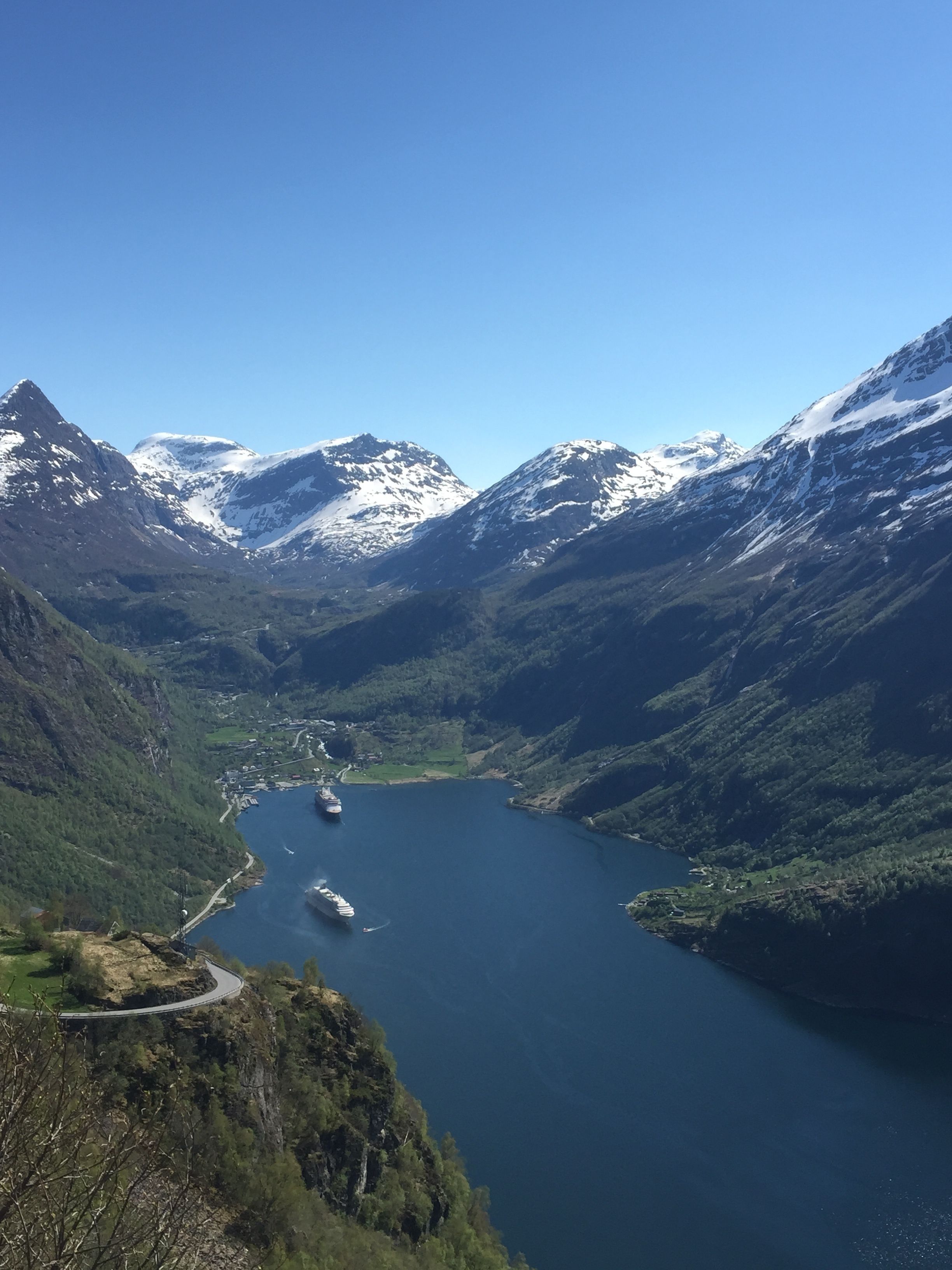 A mountainous landscape with a lake and a road curving through the valley.