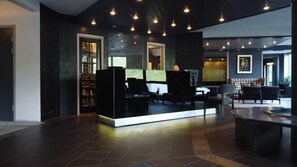 A modern lobby with a reception desk, seating area, and a large window. - Havila Hotel Geiranger (Stranda)