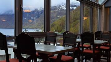 A restaurant with large windows offering a view of a mountainous landscape and a lake.