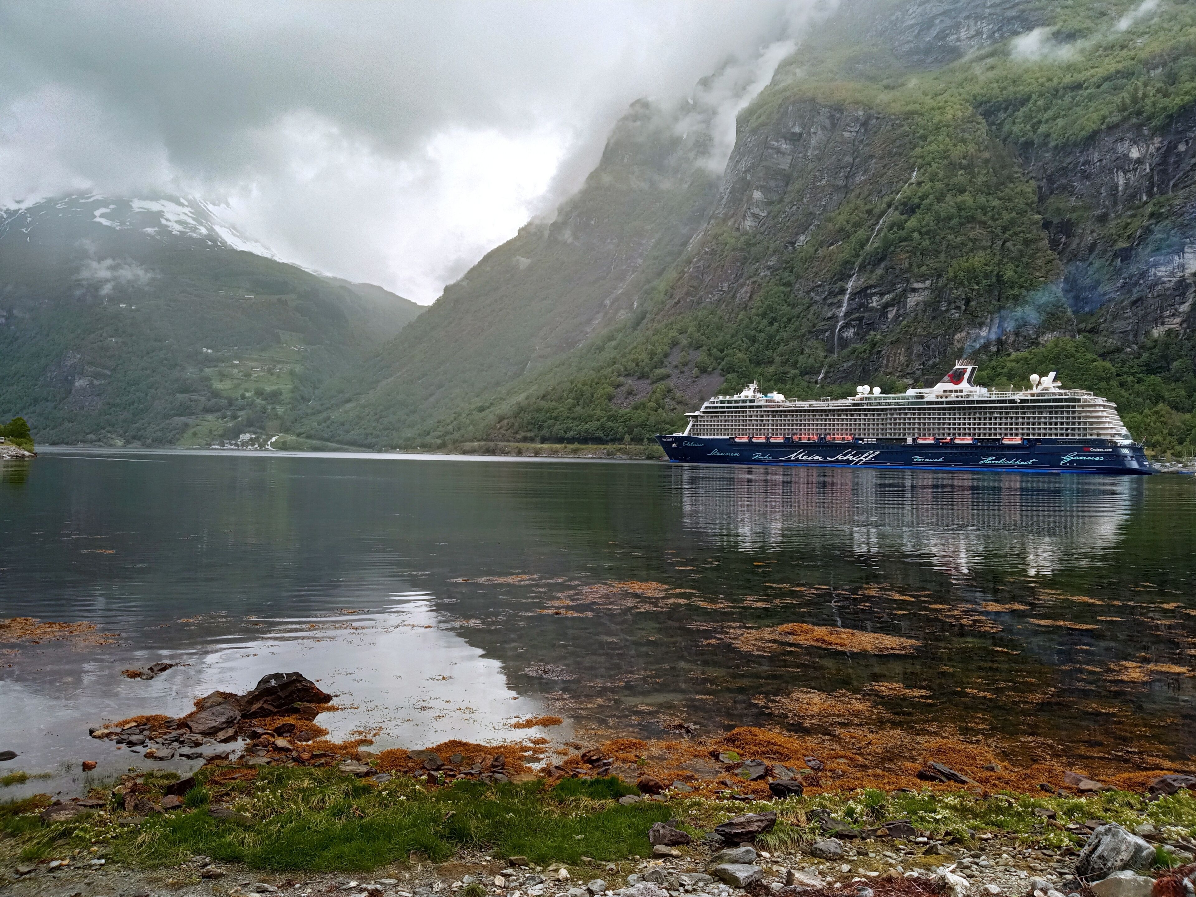 Un crucero amarrado en un puerto con terreno montañoso al fondo.