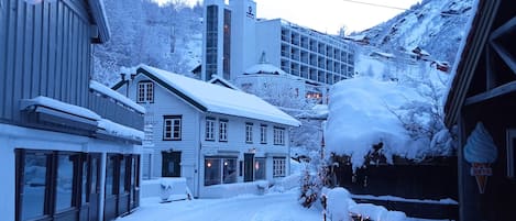 A snow-covered street with buildings, including a hotel and a restaurant.