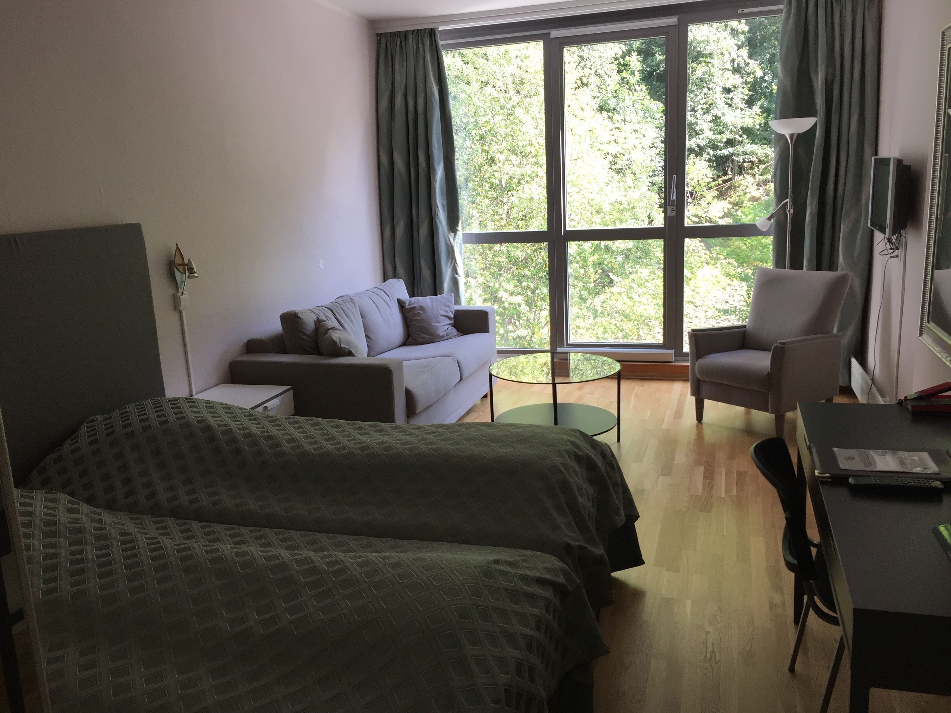 A hotel room with two beds, a sofa, a desk, and a chair.