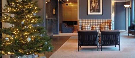 Una hall moderna con un albero di Natale, un'area salotto e un'opera d'arte incorniciata al muro.