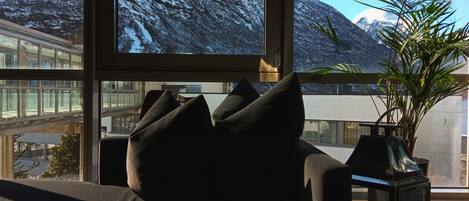 Una habitación con vistas a montañas nevadas a través de amplios ventanales.