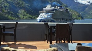 A cruise ship docked at a port with a mountainous backdrop. - Havila Hotel Geiranger (Stranda)