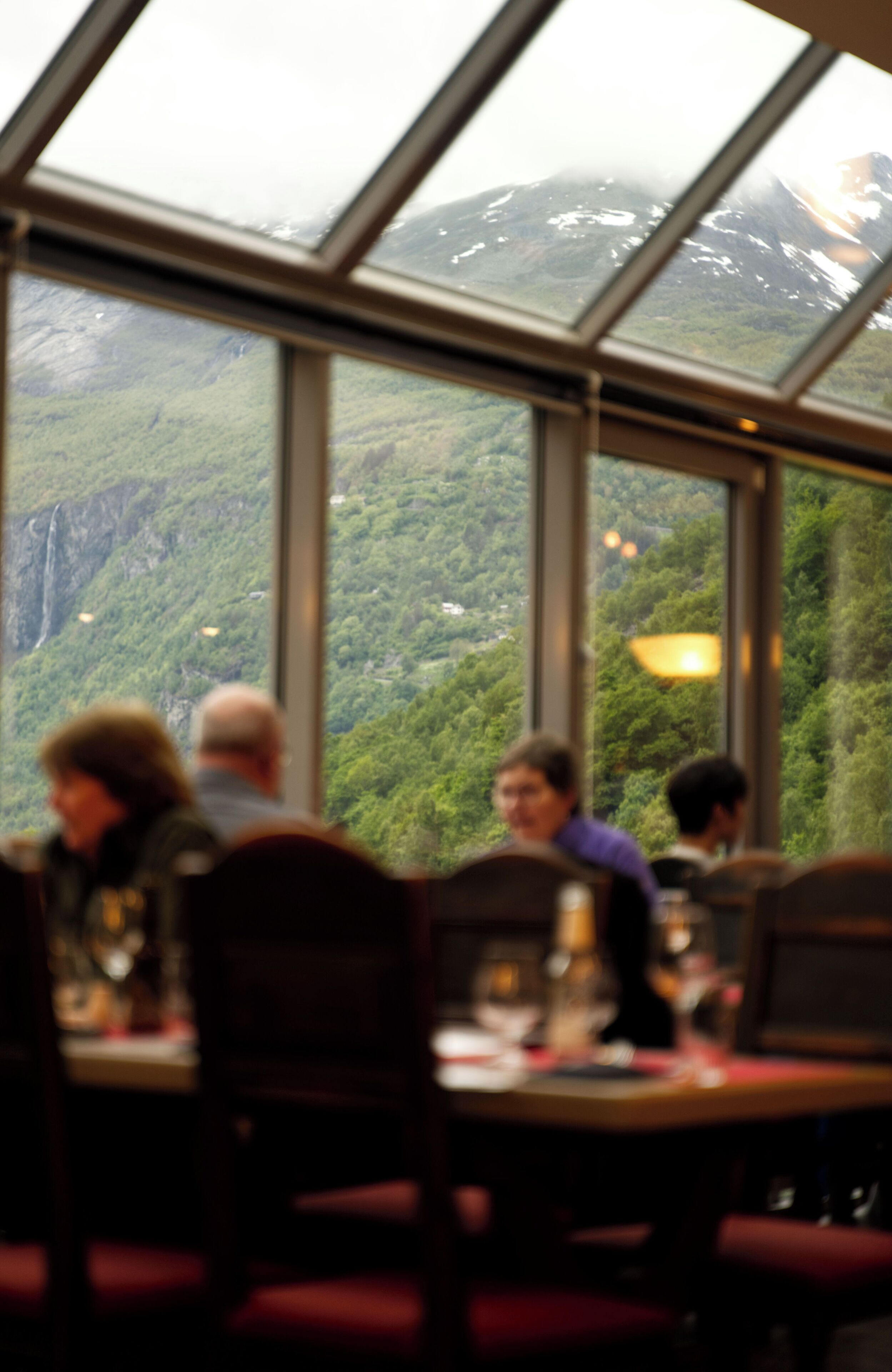 Restaurante com grandes janelas que oferecem vista para uma paisagem montanhosa.