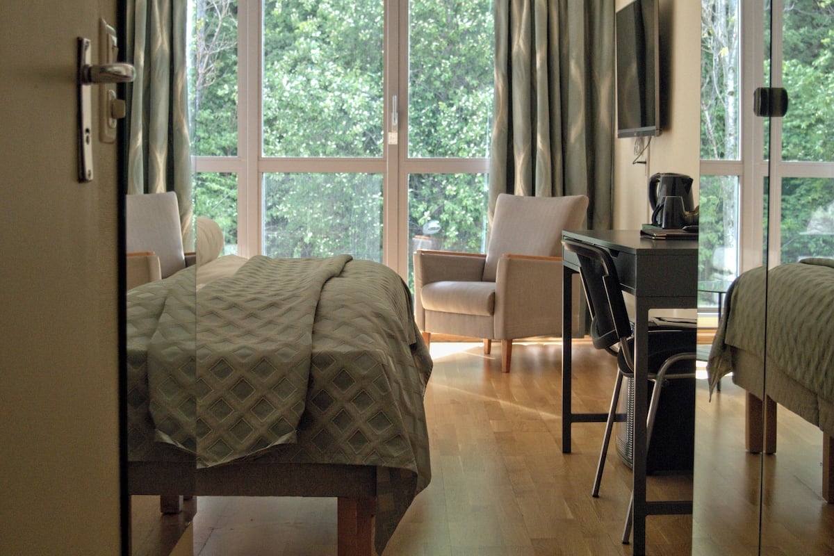A hotel room with a bed, a desk, a chair, and a TV.