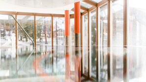 Un espace intérieur moderne doté de murs en verre et d’un sol réfléchissant, avec une colonne centrale et une main courante en métal.