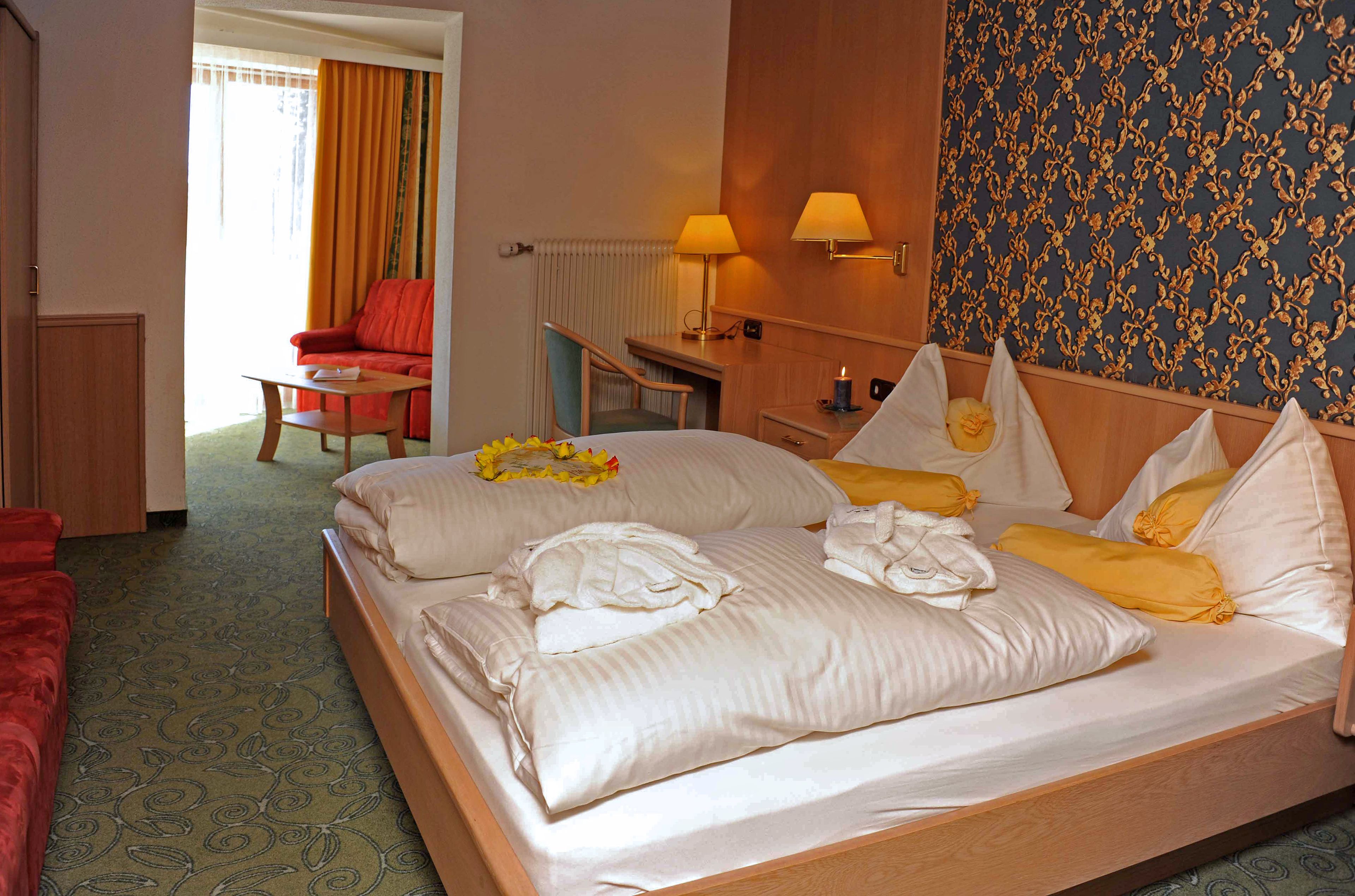 A hotel room with a large bed, a desk, a chair, and a red sofa.