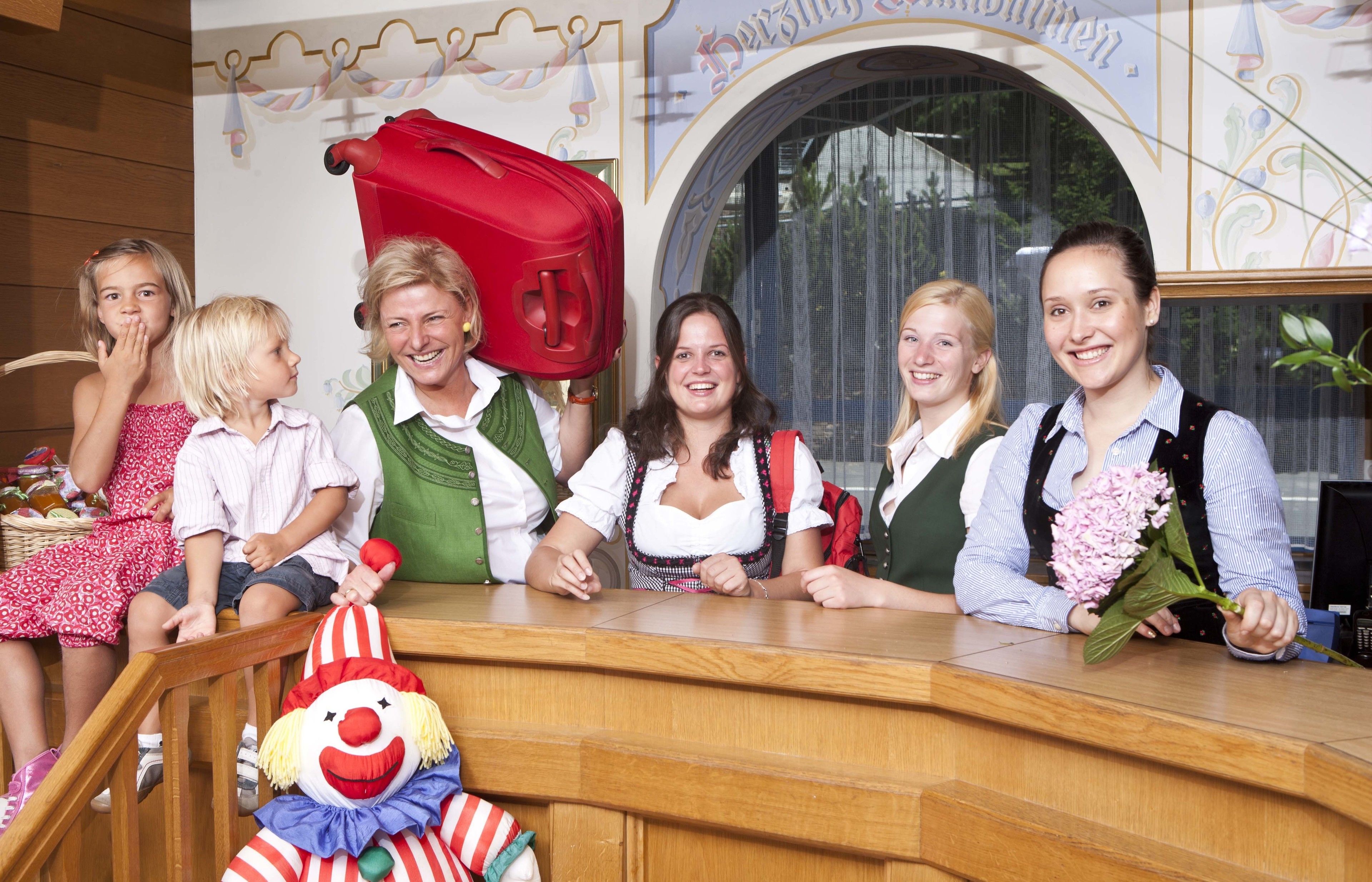 A group of people seated at a wooden counter with a clown figure in front.