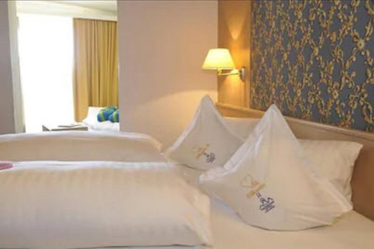 Habitación de hotel con dos camas, una lámpara y un papel tapiz estampado.